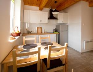 a kitchen with a wooden table with chairs and a refrigerator at Zorza in Sztutowo