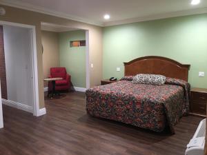 um quarto com uma cama e uma cadeira vermelha em American Inn & Suites LAX Airport em Inglewood