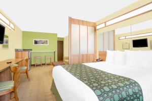 TuscumbiaにあるMicrotel Inn & Suites by Wyndham Tuscumbia/Muscle Shoalsの大きなベッドとデスクが備わるホテルルームです。