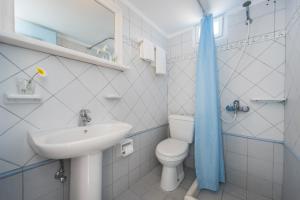 a white bathroom with a sink and a toilet at Hotel Olympia in Karterados