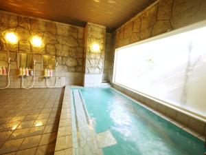 a swimming pool in a room with a stone wall at Hotel Route-Inn Susono Inter in Susono