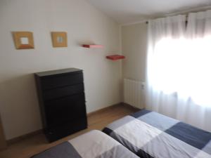 a bedroom with two beds and a dresser and a window at Apartamento El Rasero in Riaza