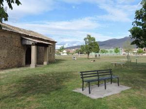 a park bench sitting in the grass next to a building at Apartamento El Rasero in Riaza