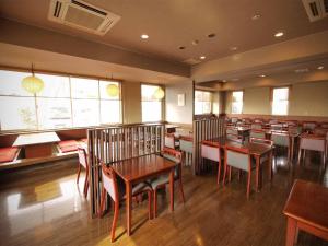 um restaurante com mesas e cadeiras de madeira e janelas em Hotel Route-Inn Susono Inter em Susono