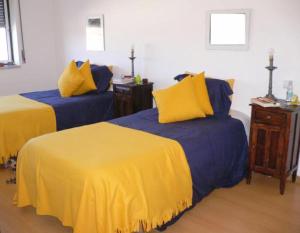 two beds with blue and yellow sheets in a room at Apartment Peniche swimming pool in Peniche de Cima