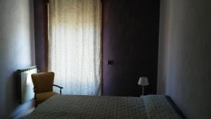 una camera con un letto e una sedia e una finestra di B&B PinkHouse a Milazzo