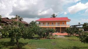 a house with a red roof and a yard with trees at Harum Manis Country House in Kangar