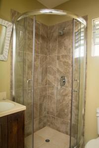 a shower with a glass door in a bathroom at Believe Caribbean Apartment in Bridgetown