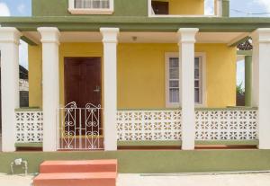a yellow house with a door and a fence at Believe Caribbean Apartment in Bridgetown +10 photos