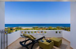 balcón con mesa, sillas y vistas al océano en Gennadi Beach Villas - Waterfront Luxury Retreat with Private Beach, en Gennadi
