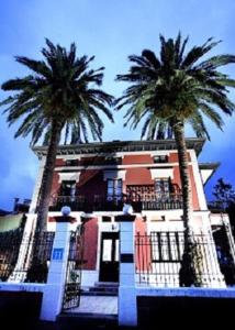 two palm trees in front of a building at Hotel Casa de Indianos Don Tomás in Nueva de Llanes