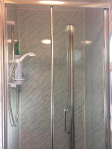 a shower with a glass door with a shower head at Bouvrie Guest House in Hereford