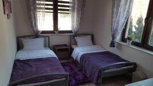 2 łóżka w małym pokoju z 2 oknami w obiekcie DobraNocka w mieście Kaleń