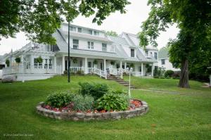 une grande maison blanche avec un lit fleuri dans la cour dans l'établissement Chestnut Inn, à Niagara Falls