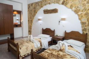 a bedroom with two beds and a stone wall at Konaki Apartments in Maleme