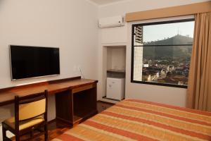 a hotel room with a television and a bed at Real Palace Hotel in Santa Rita do Sapucaí