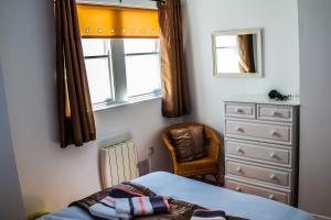 a bedroom with a bed and a dresser and a window at Tower View Apartment in Cushendall