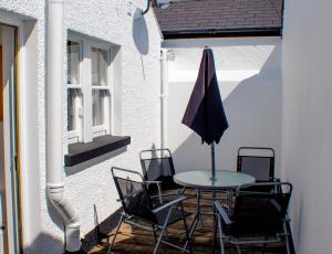 a patio with a table and chairs and an umbrella at Tower View Apartment in Cushendall