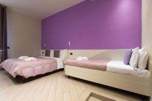 two beds in a room with a purple wall at Affittacamere Serena in Piacenza