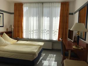 1 dormitorio con cama, escritorio y ventana en Parkhotel Friedrichstrasse, en Giessen