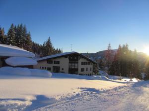 a house covered in snow with the sun behind it at Top 6 in Mühlbach am Hochkönig