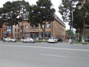 een straat met auto's geparkeerd voor een gebouw bij Umariyon in Panjakent