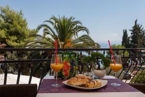 a table with a plate of food and two glasses of orange juice at Villa Aequum in Trogir