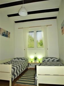 a bedroom with two beds and a table and a window at Apartment Maslina in Premuda