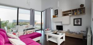 a living room with a purple couch and a large window at La Espiga in Cortos