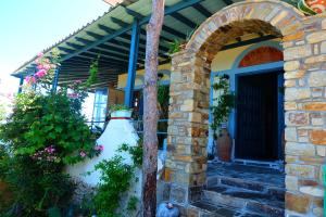 Zugang zu einem Haus mit einem Torbogen und Blumen in der Unterkunft Pension Galini in Armenistis