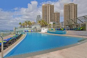 een groot zwembad met blauwe stoelen en gebouwen bij Soul on the Esplanade - HR Surfers Paradise in Gold Coast