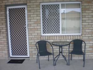 three chairs and a table in front of a window at Molika Springs Motel in Moree