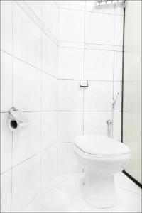 La salle de bains blanche est pourvue d'une douche et de toilettes. dans l'établissement Pousada Solarium UNIDADE 1 ECONOMICA-BÁSICA, à Guarujá
