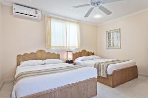a bedroom with two beds and a ceiling fan at BUTTERFLY GARDEN BOUTIQUE RESIDENCES Apts and villas, A Lifestyle Destination Ex Lg 1-3 bedroom units , Full kitchen, 2 Full bathrooms, Rain shower, Spa bath, FREE BBQ, Free fast fiber optic WIFI, Staff 24-7 in Pattaya South +78 photos