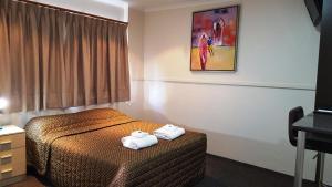 Una habitación de hotel con una cama con toallas. en The Commercial Hotel Motel, en Chinchilla