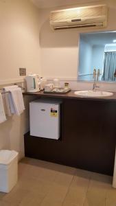 a bathroom with a sink and a counter with a dishwasher at The Commercial Hotel Motel in Chinchilla