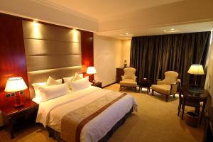 um quarto de hotel com uma cama grande e cadeiras em Rongjiang Hotel em Jieyang