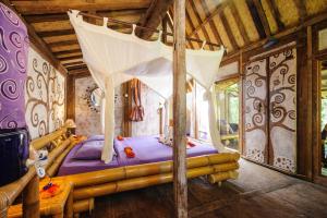 ein Schlafzimmer mit einem Himmelbett in einem Haus in der Unterkunft Swasti Eco Cottages in Ubud