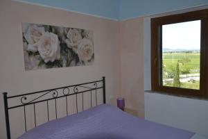 sypialnia z łóżkiem z fioletową pościelą i oknem w obiekcie Podere S.Giulia - casale Banditelle w mieście Venturina Terme