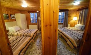 two beds in a room with wooden walls at Christys Palace Hotel in Pedoulas