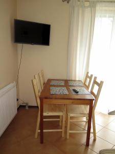 a dining room table with chairs and a television on the wall at Wysoka Fala in Jastrzębia Góra