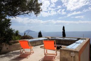 two orange chairs sitting on a patio looking out over the ocean at Alicudi Giardino dei Carrubi- al gradino 365 in Alicudi