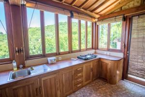 a kitchen with a sink and a bunch of windows at Bruce's Hideout in Bumbang