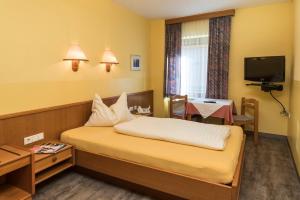 ein Hotelzimmer mit einem Bett und einem TV in der Unterkunft Frühstückspension Meyer, Familie Orthacker in Graz