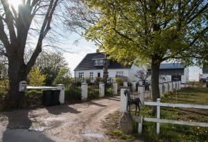 a white house with a fence and a tree at Idestrup Bed and Breakfast in Idestrup