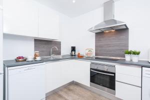 a kitchen with white cabinets and a sink at Quinze Germans in Port d'Andratx