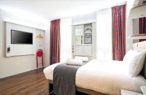 a bedroom with a bed and a tv on a wall at Point A Hotel London Shoreditch in London