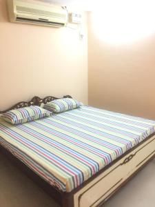 a bed with striped sheets and pillows in a room at Sterling Homes Near Apollo/Shankara in Chennai
