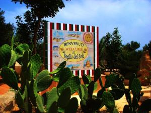 un gran cartel en un jardín con un cactus en Baglio Del Sole en San Vito lo Capo