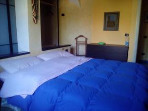 un grande letto in una stanza con un piumone blu di Villa Pontes a Marina di Orosei